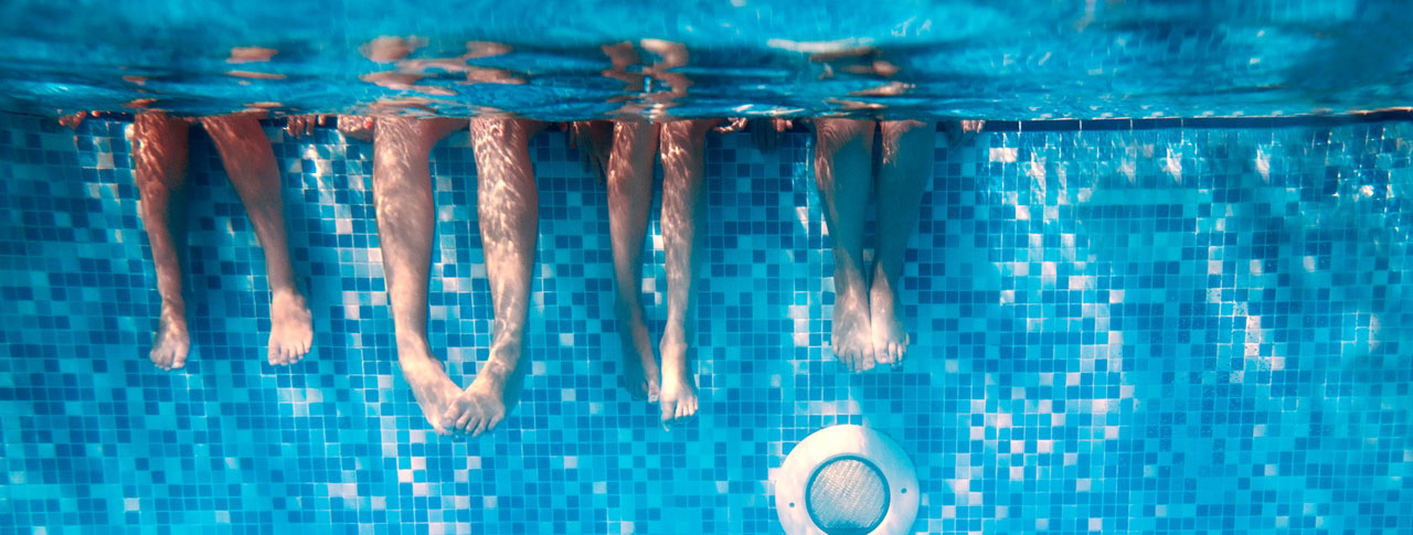 Children's and adults legs underwater in swimming pool